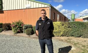 éleveur de porc devant ses bâtiments d'élevage