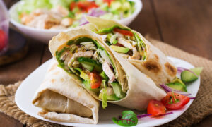 Une tortilla avec du poulet et des légumes dans une assiette