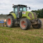 Un tracteur avec un outil attelé au travail au champ