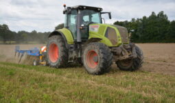 Un tracteur avec un outil attelé au travail au champ