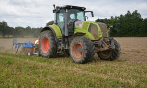 Un tracteur avec un outil attelé au travail au champ