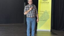 Une personne sur scène avec un micro devant un kakemono Eureden